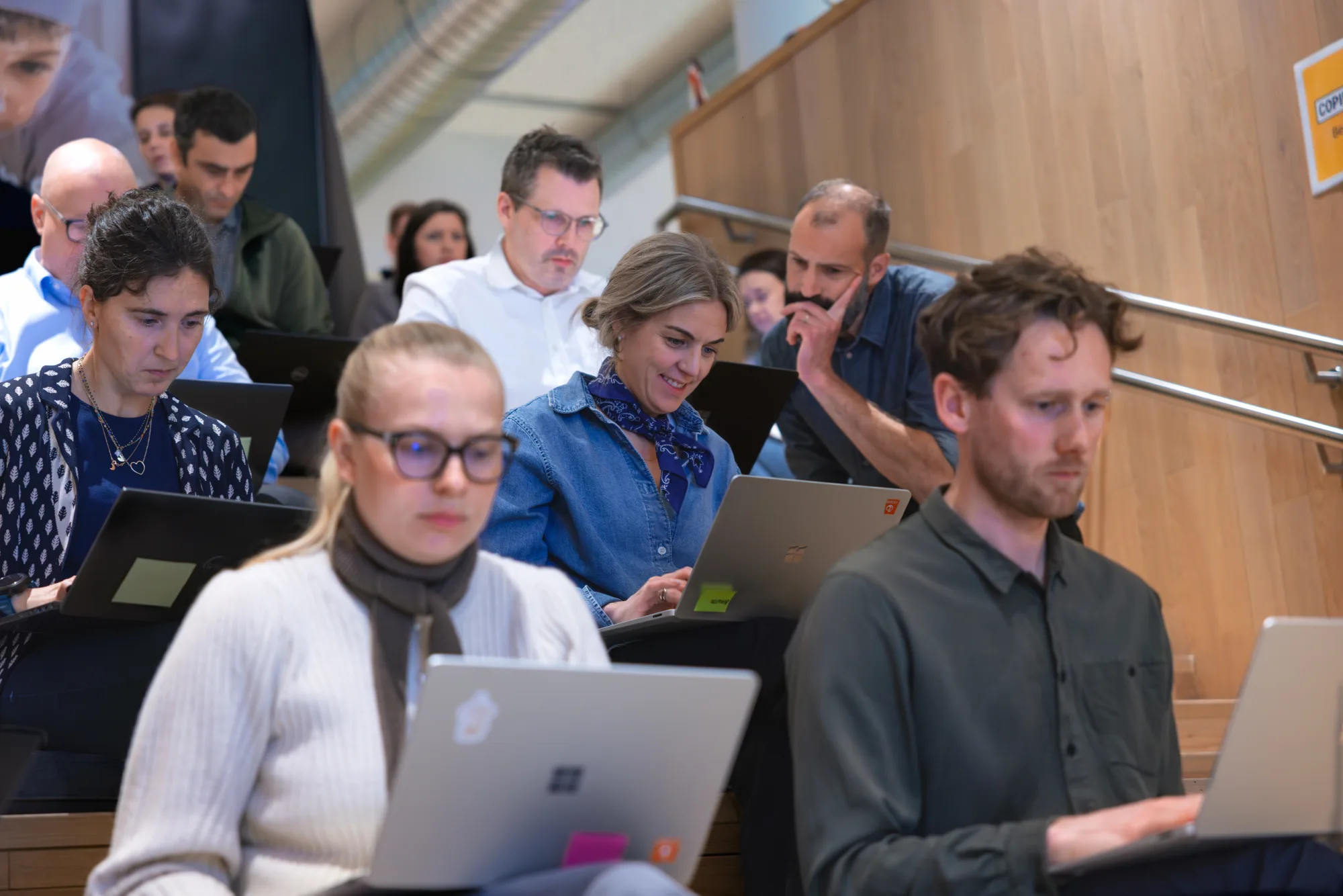 Geconcentreerde deelnemers werken op laptops tijdens een AI-trainingssessie